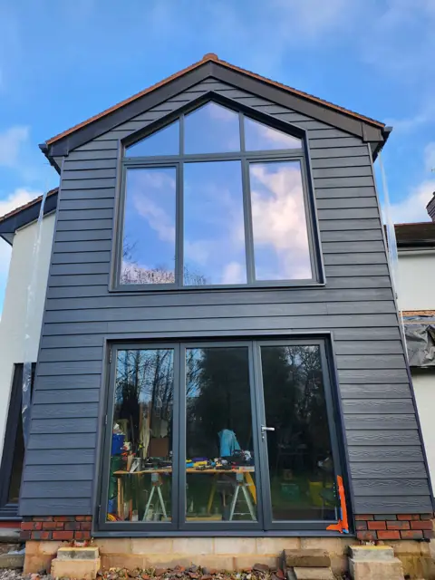 A dark-clad gable with full-height glazing — CG Cladding Solutions